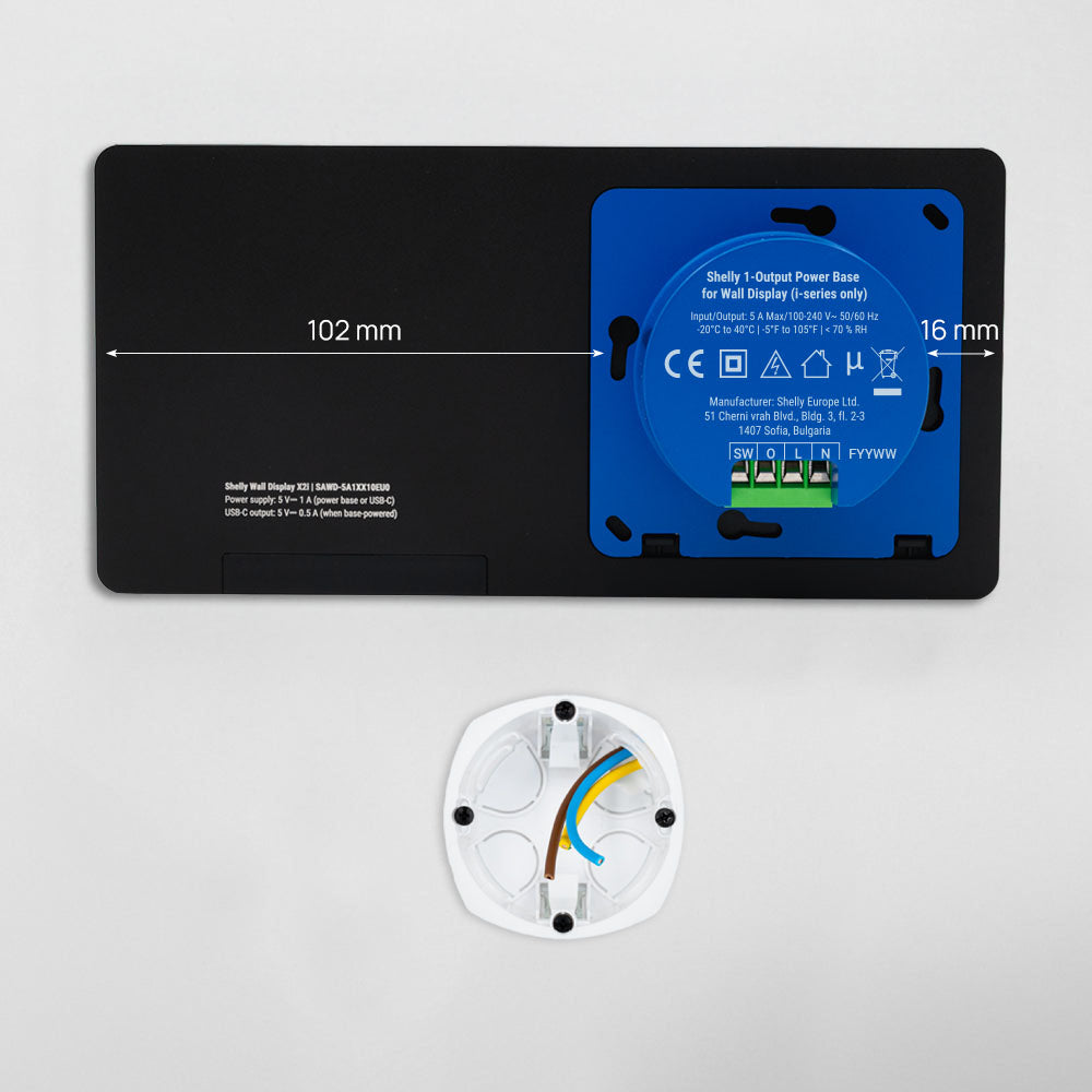 A black rectangular Shelly Wall Display X2i base with a blue "Output Power Base" label and wiring terminals. Below, a white circular wall mount with exposed wires. Dimensions: 102 mm x 16 mm.
